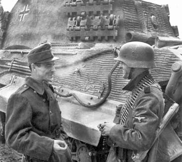 Венгерский солдат курит вместе с членом пулеметного расчета части СС у танка в 1944 []